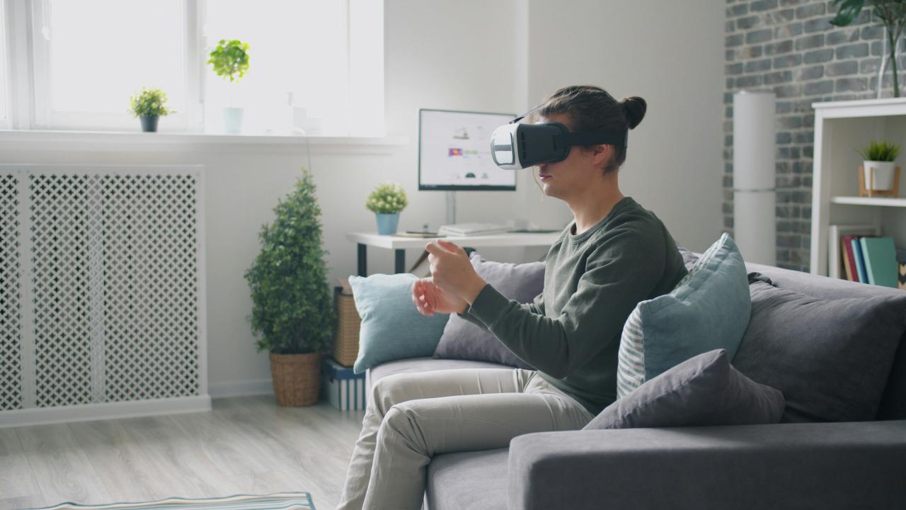 Man wearing vr headset playing video game on couch.