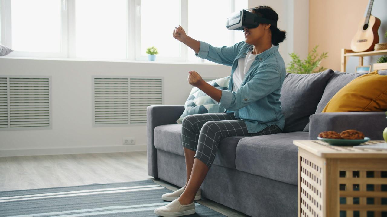 Woman wearing vr headset playing game on couch